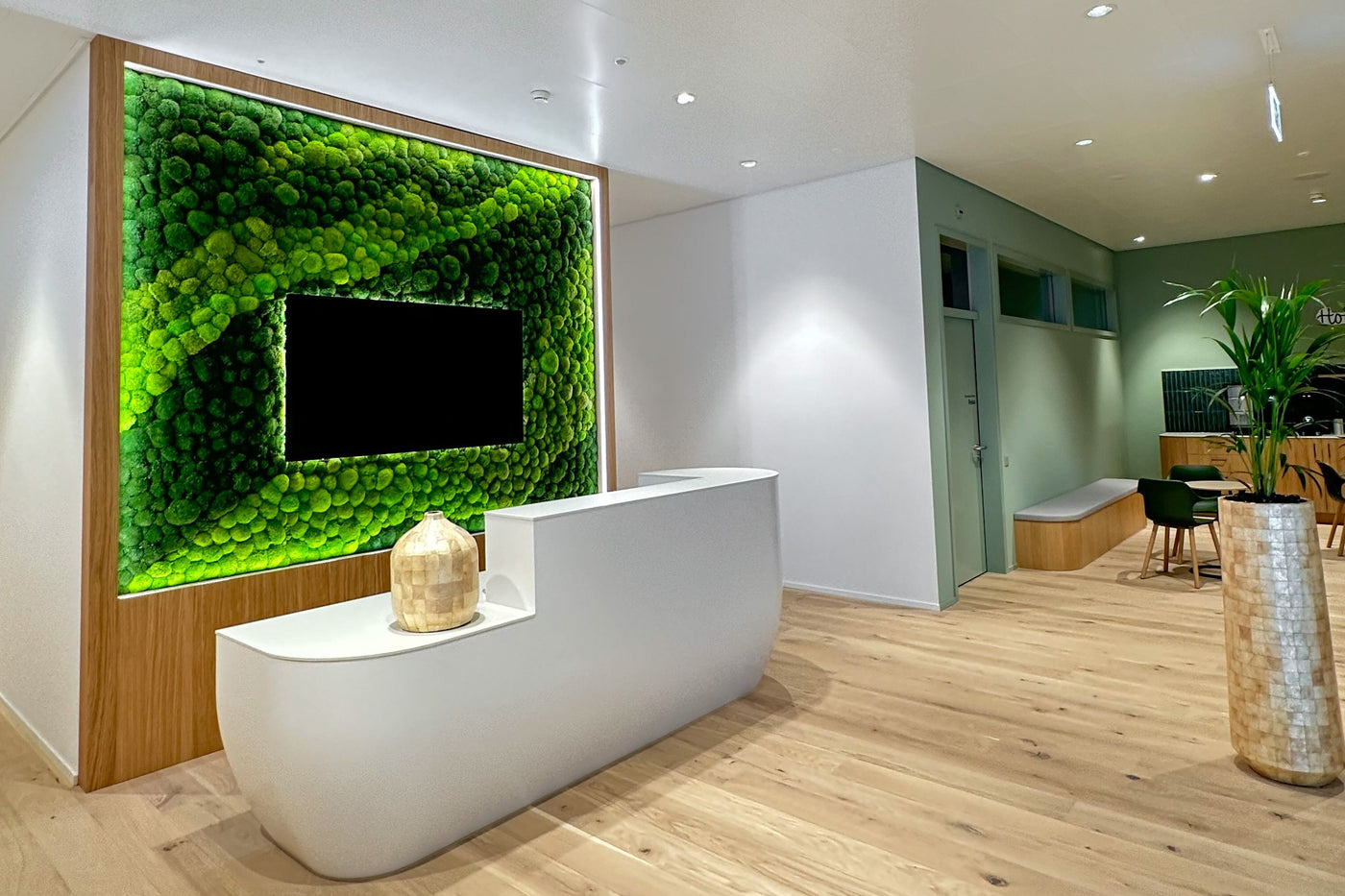Feature Bild: Kugelmooswand in verschiedenen Grüntönen, integriertem TV und LED-Lichter für Empfangsbereich der Bühler AG
